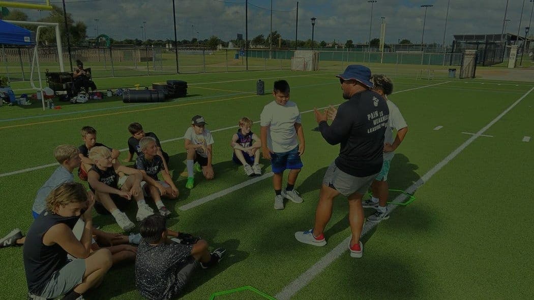 Coach Bob coaching a group of young athletes gathered on the practice field.